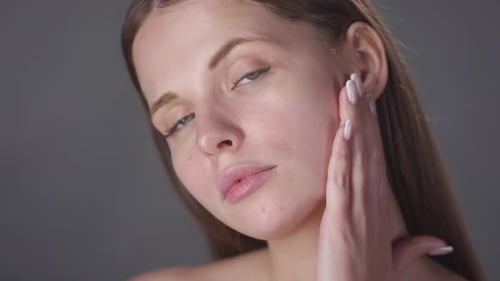 Woman Applying Cream To Her Face