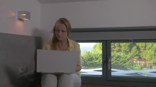 Woman Using Laptop Computer Indoors by Window