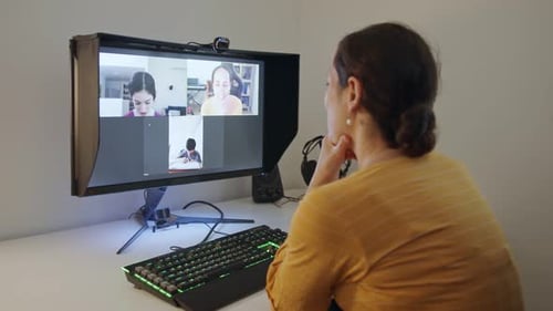 Woman Attends Video Call with Students on Monitor