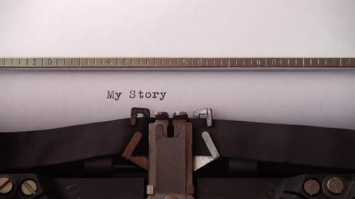 Typing phrase My Story on retro typewriter. Close up.
