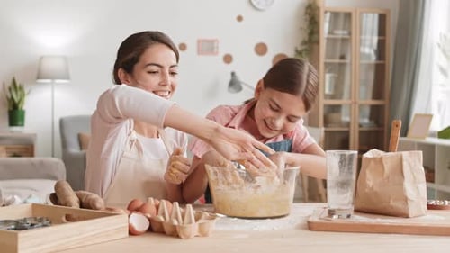 Woman and Child Kneading Dough Together at Table