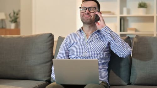 Man Talking on Phone While Using Laptop
