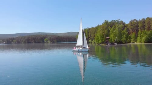 Aerial View of Sailing Boat Walking Alone on a Wide Blue Clear Lake on a Sunny Morning