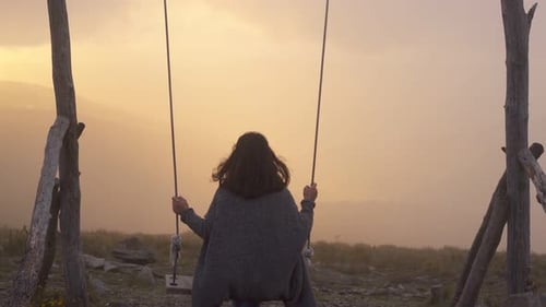 Femme se balançant sur une balançoire à Lousa Baloico au coucher du soleil, Portugal