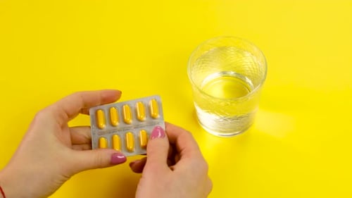 Yellow Capsules and Water on Yellow Background