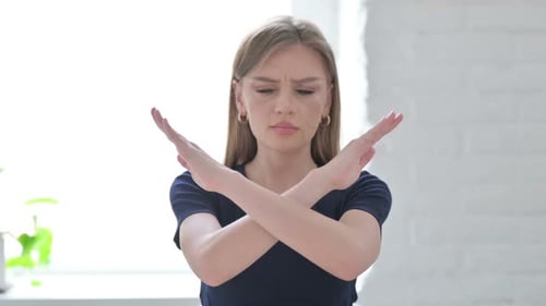 Young Woman Makes Stop Gesture with Crossed Arms