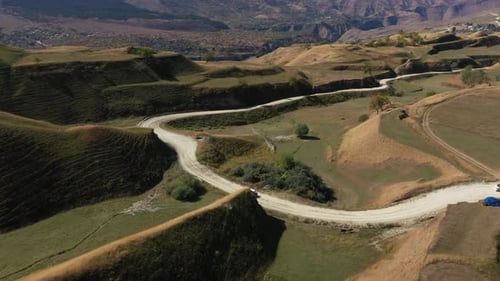 Cars Drive Through Rural Mountain Road Landscape