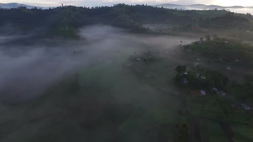 Toma aérea de pueblos cubiertos por la niebla en Uganda