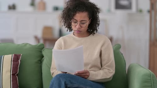 Woman Reads Documents on Couch in Bright Room