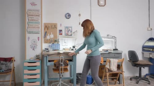 Woman Puts on Apron in Bright Workshop