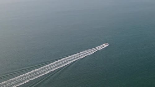 Isolated speedboat leaves white wake trail over blue and calm sea water. Aerial view