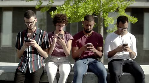 Front View of Focused Friends Using Smartphones in Park