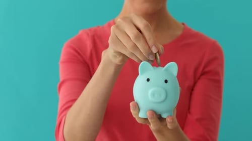 Positive Frau setzt Münze in Sparschwein Planung Budget Finanzielle Einsparungen