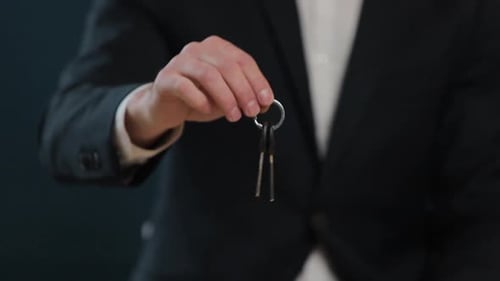 Zeitlupe eines männlichen Mittelteils in formeller Jacke, der Hausschlüssel in der Hand hält und vor die Kamera zeigt