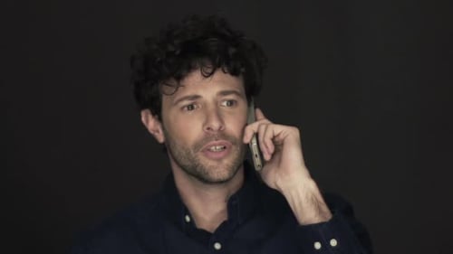 Man Talking on Mobile Phone Against Dark Background