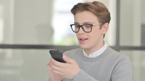 Young Adult Celebrating While Looking At Phone Indoors