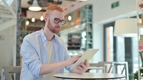 Attractive Redhead Man with Digital Tablet in Cafe