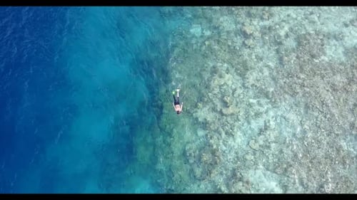 Romantic couple tanning on luxury lagoon beach holiday by blue green lagoon and white sand backgroun