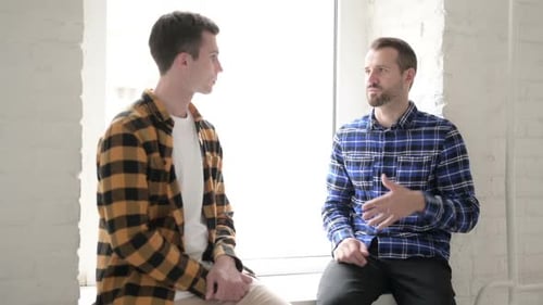 Two Men Engaging in Conversation by Window