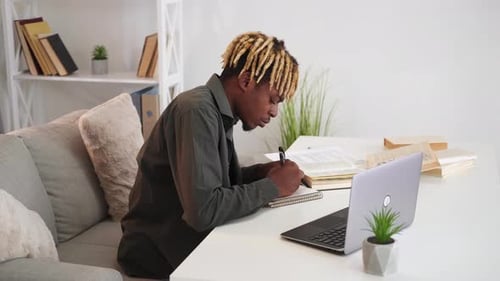 Young Adult Studying and Writing in Notebook
