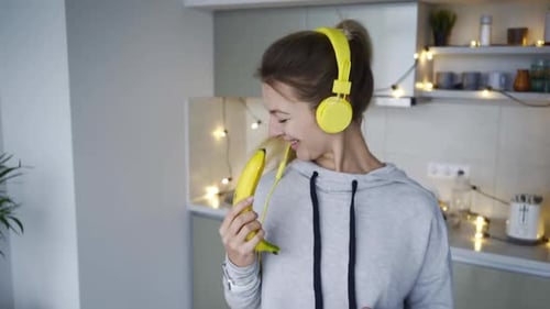 Woman Singing and Dancing with Banana in Kitchen