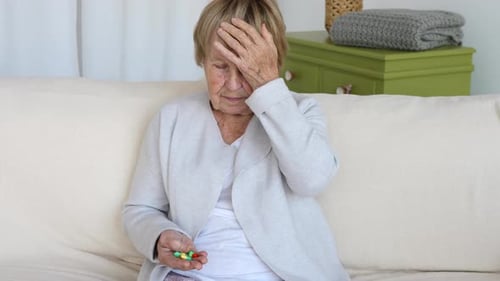 Senior Woman Holding Pills with Headache