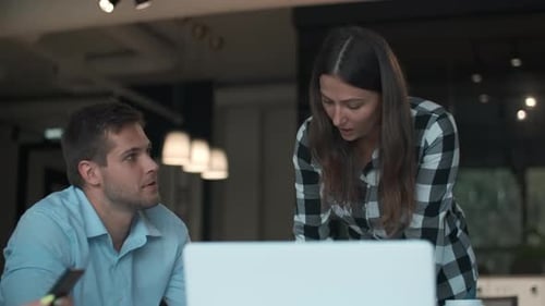 Man and Woman Collaborating on Laptop in Modern Office