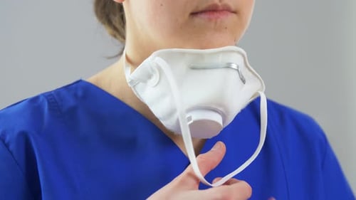 Adult Puts on White N95 Protective Mask