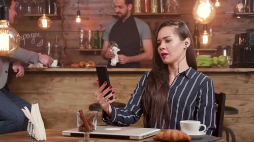 Young Businesswoman Engaged in a Video Call in a Coffee Shop