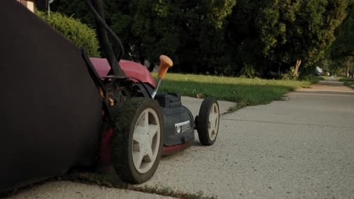 Lawnmower on Sidewalk near Green Suburban Lawn