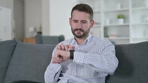 Man Using Smartwatch on Couch in Living Room