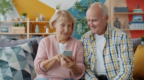 Senior Couple Using Smartphone Together on Couch