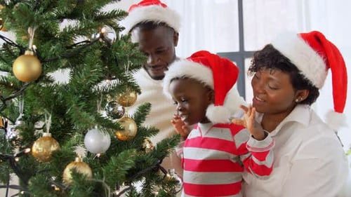 Family Decorating Christmas Tree in Santa Hats