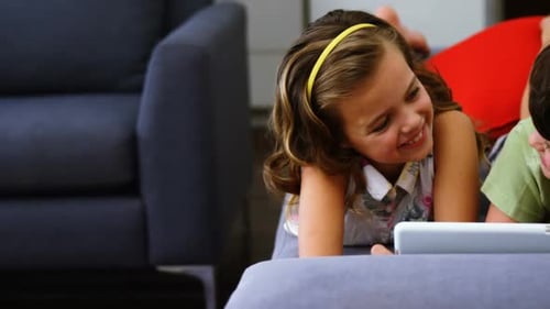 Children Using Tablet While Lying on Couch