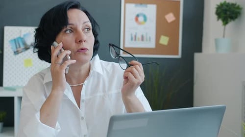 Joyful Business Lady Chatting on Mobile Phone and Smiling Working Alone in Office