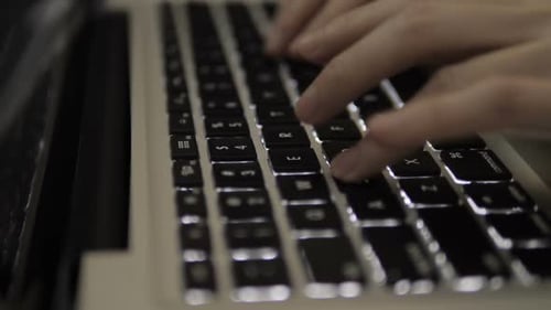 Hands Typing on Illuminated Laptop Keyboard in Office