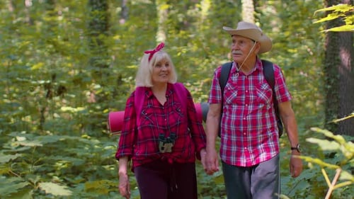 Senior Couple Hiking Hand-in-Hand Through Green Forest