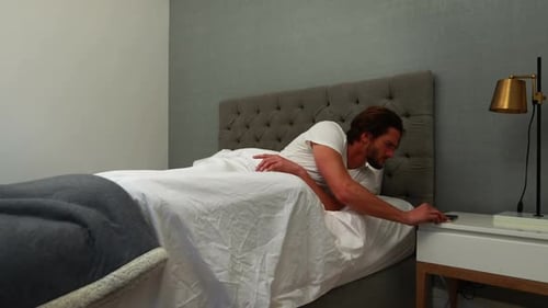 Man Waking Up and Stretching in Bed