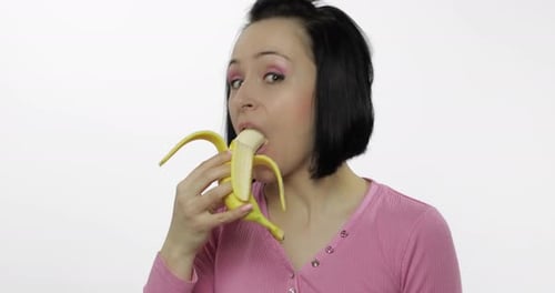 Woman Enjoys Eating a Banana in Studio Setting