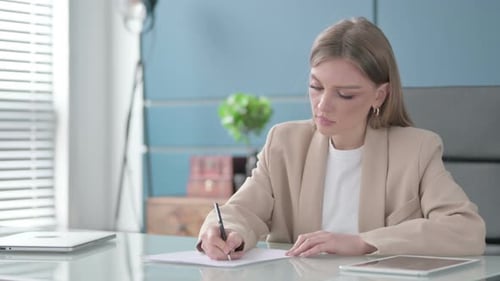 Businesswoman Writing on Paper in Office