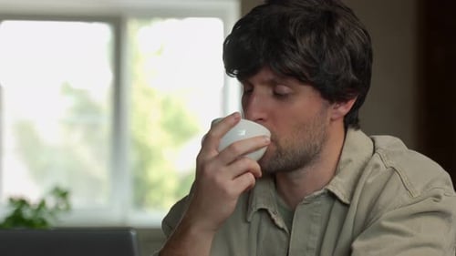 Man Drinking Coffee and Looking Thoughtful Indoors