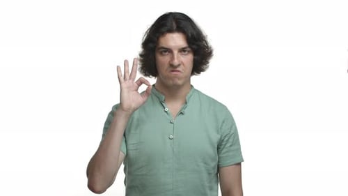 Attractive Hispanic Man with Long Hairstyle Wearing Green Shirt Showing Okay Sign and Nodding in
