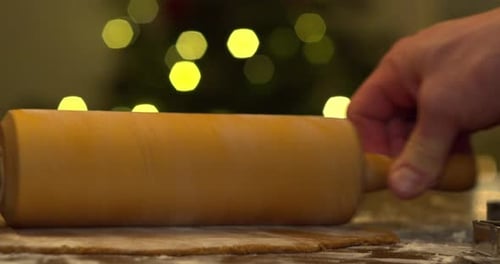 Flattening gingerbread dough with rolling pin on a floured table