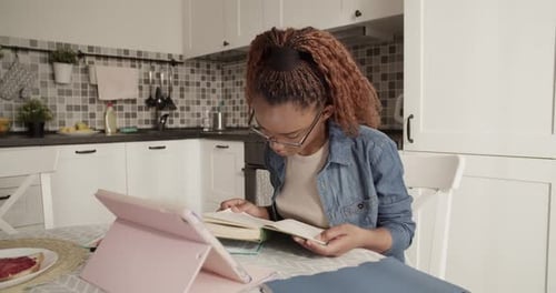 Young Adult Reading a Book in the Kitchen