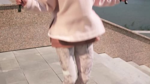 Woman with Headphones Jump Roping By River in City