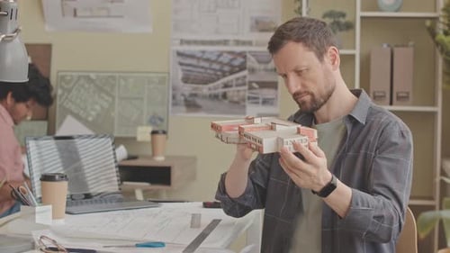 Architect Inspecting Scale Model in Office