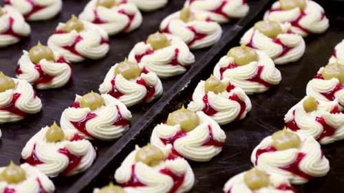 Kuchen mit Erdbeer- und Orangenmarmelade auf dem Förderband einer Süßwarenfabrik