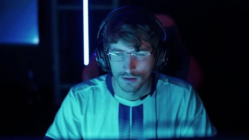 Intense Young Gamer Concentrating in Blue Lit Room