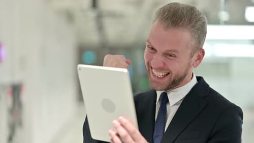 Man Celebrates Success with Tablet Computer