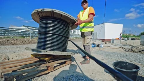 Construction Worker with Cable Spool at Construction Site